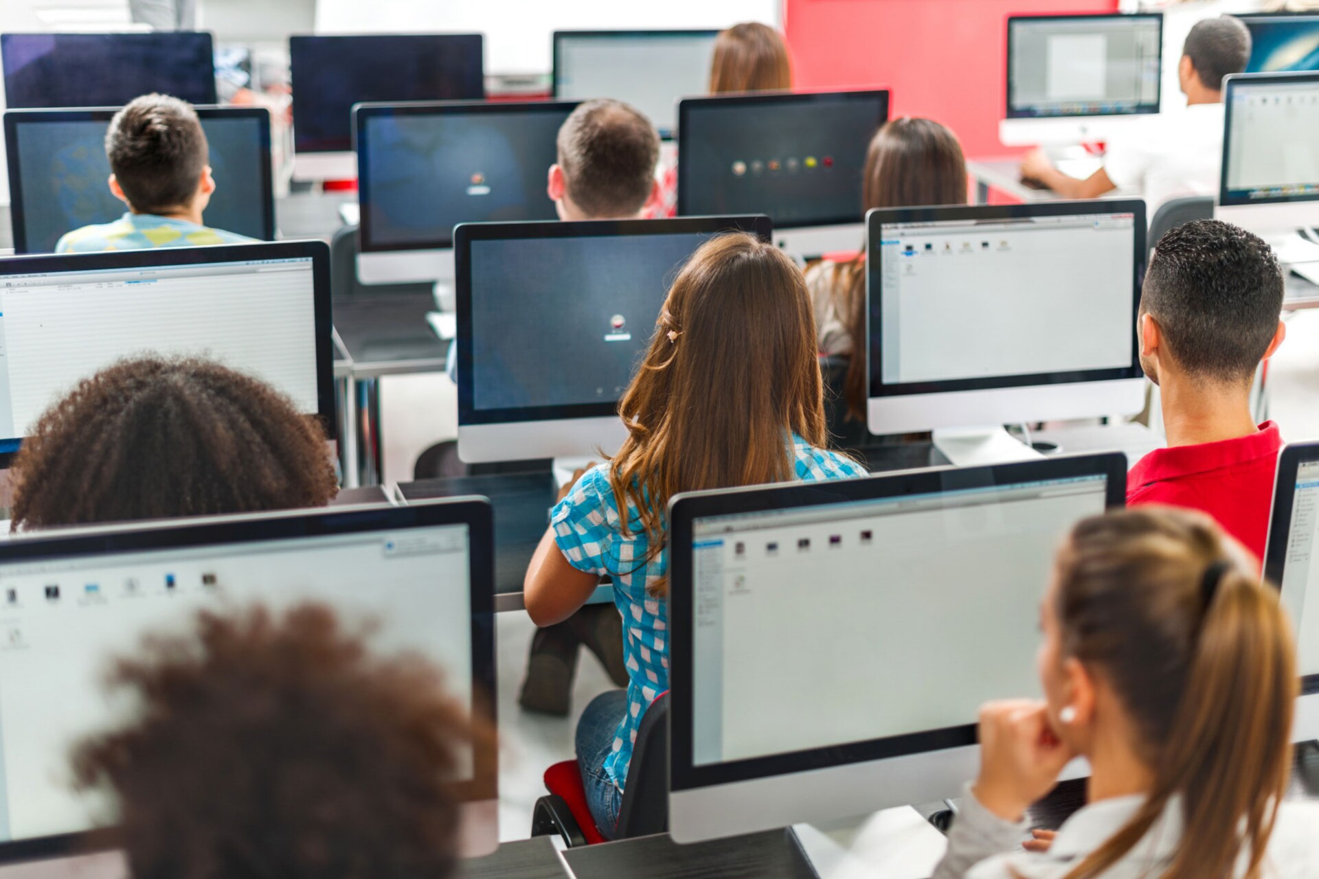 Wide shot of children at school in a computer lab learning.